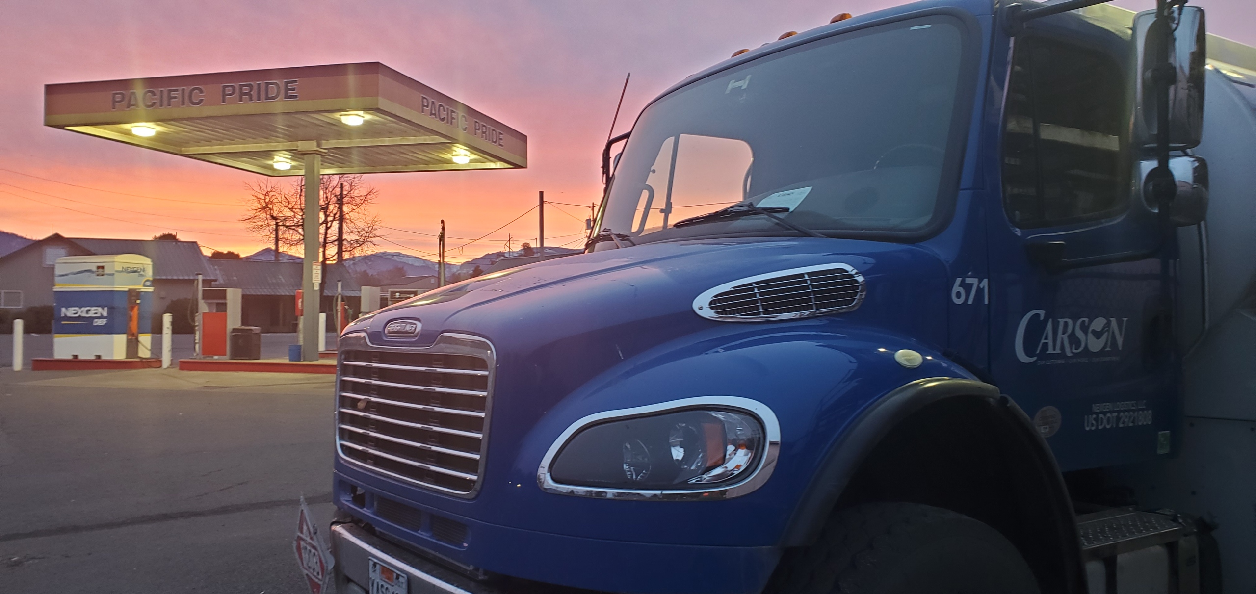 Carson truck in front of Pacific Pride cardlock station with a NEXGEN DEF pump. The sun is setting and the sky is a soft pink.